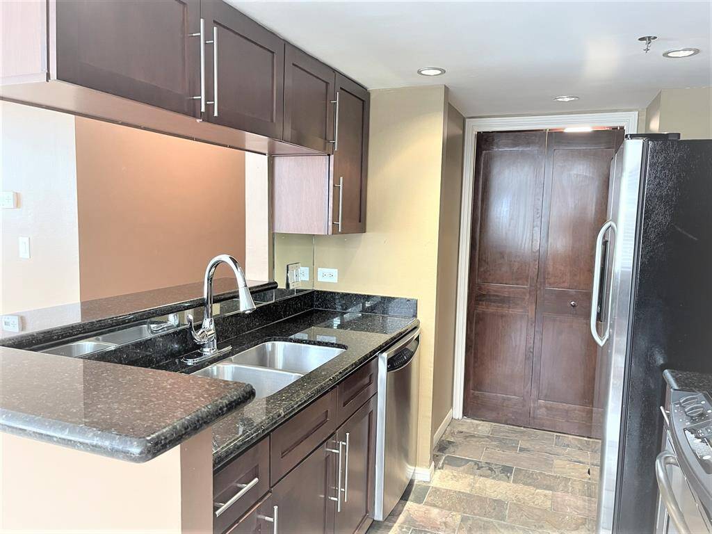 Galley kitchen arrangement with designer gooseneck faucet over stainless steel double compartment sink.