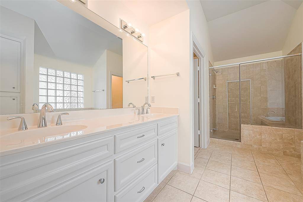 Primary bathroom suite with elongated soaking tub, privacy window and dual sinks.