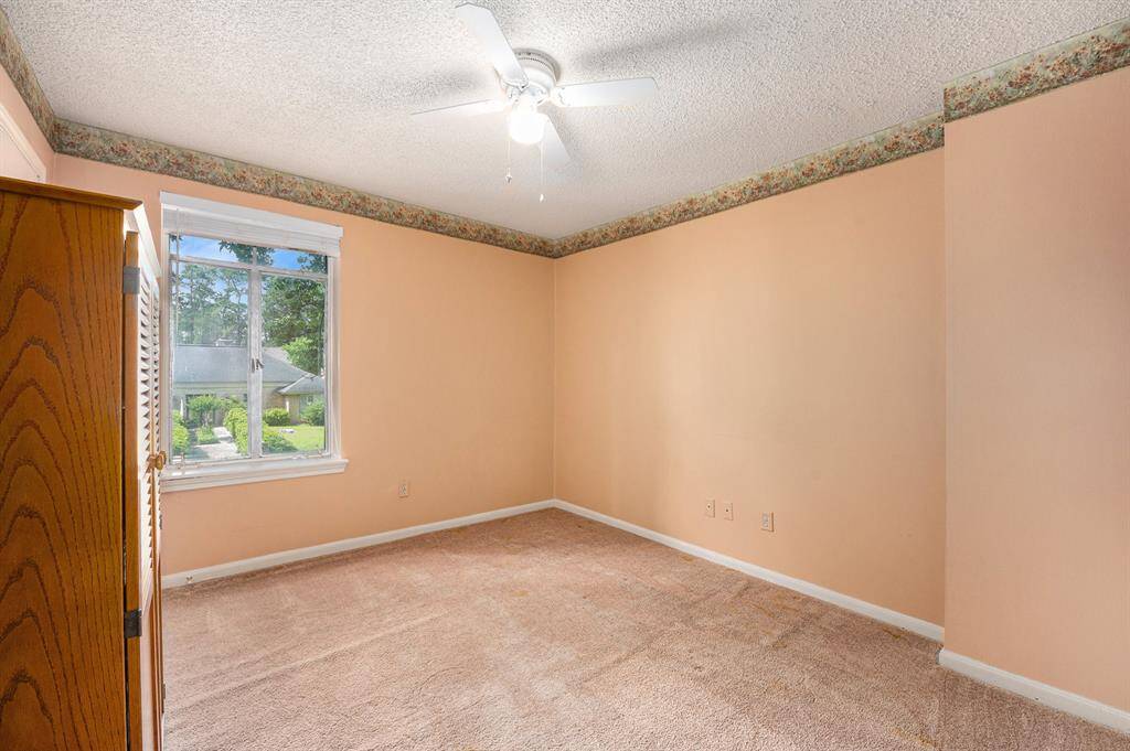 Secondary bedroom with a walk-in closet with views of the front yard.
