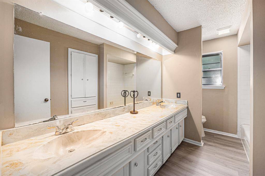 Secondary bathroom offers dual sinks, ample cabinet space, and a combination tub and shower.
