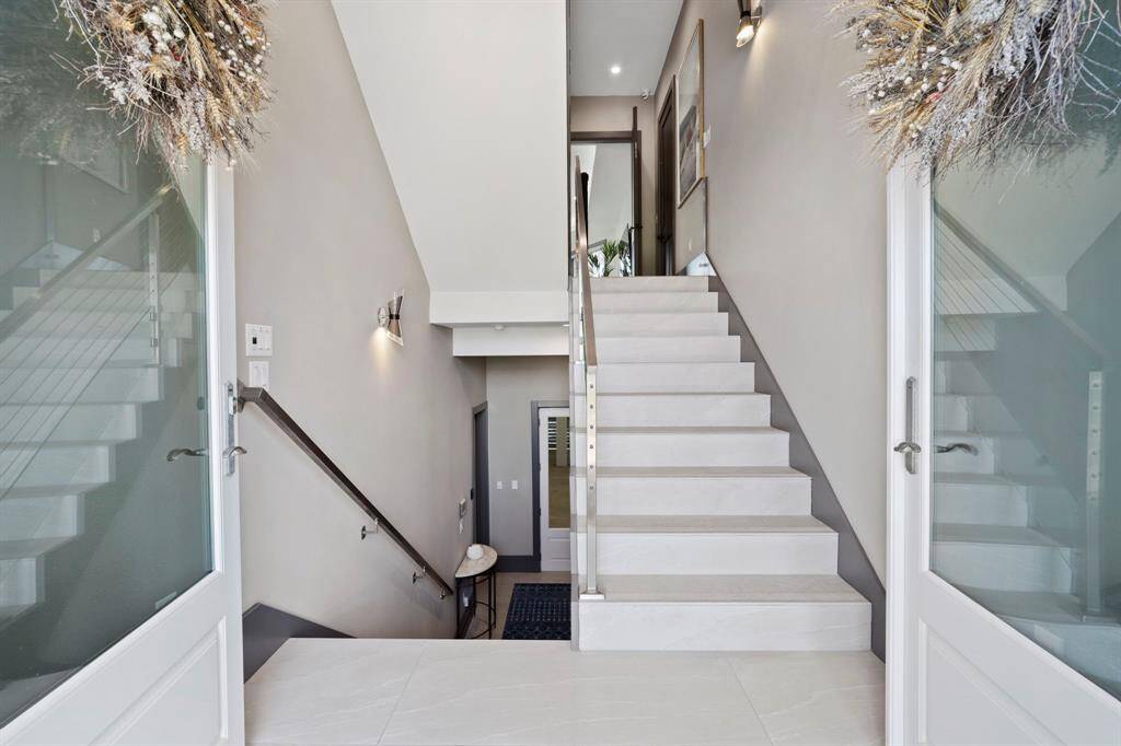 View coming in the grand entrance a landing area between the ground floor and second floor.  Stairs going down take you to garage/elevator.  Stairs going up take you to the primary bedroom, one secondary bedroom and a game room/living area.