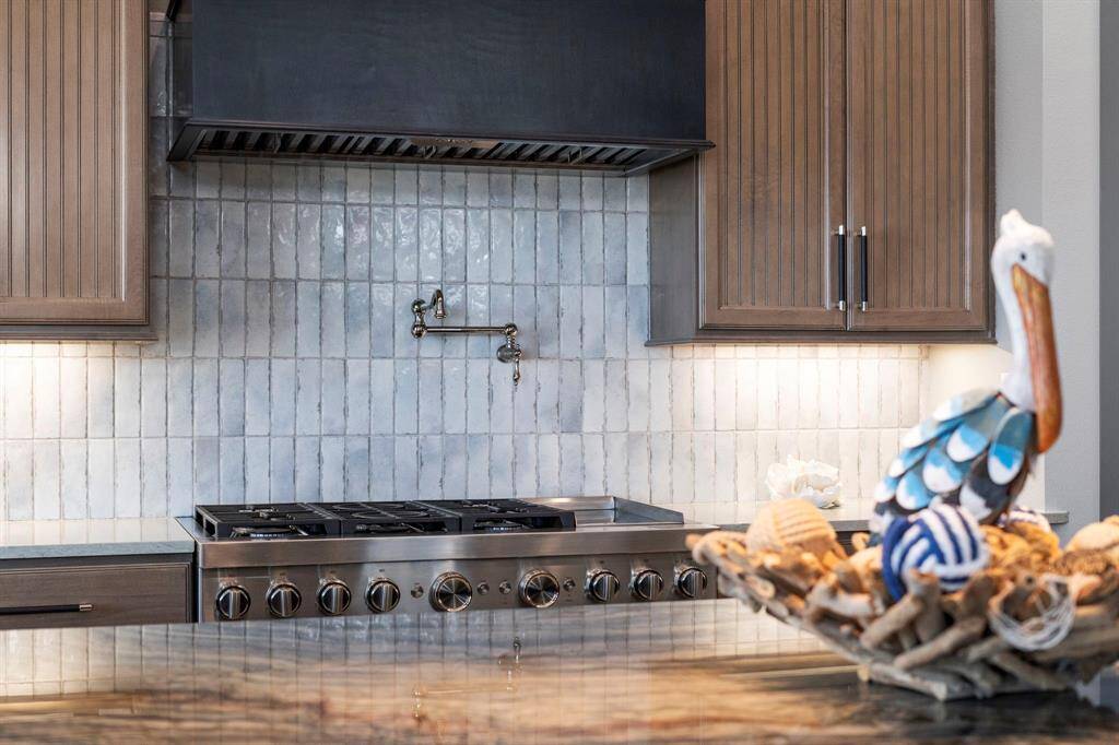 Beautiful tile backsplash mimics the blues of the ocean water. Pot-filler tap makes cooking a snap.