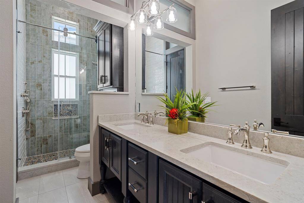 Secondary bath with double sinks and walk-in tiled shower.