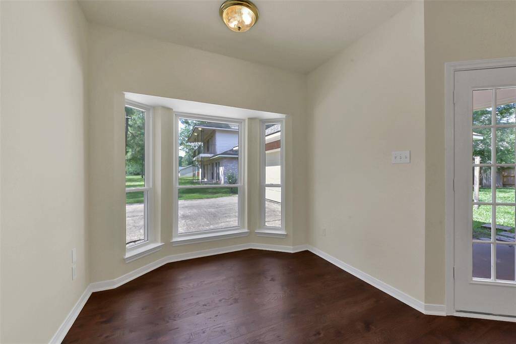 Bright room with large bay windows, hardwood floors, and a French door leading outside. Perfect for a cozy sitting area or breakfast nook.