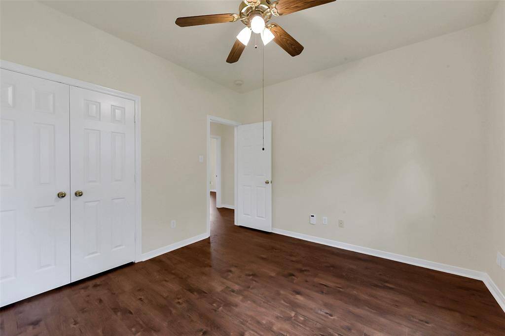 This room features hardwood flooring, neutral walls, a ceiling fan with lights, and a double-door closet, offering a bright and versatile space.