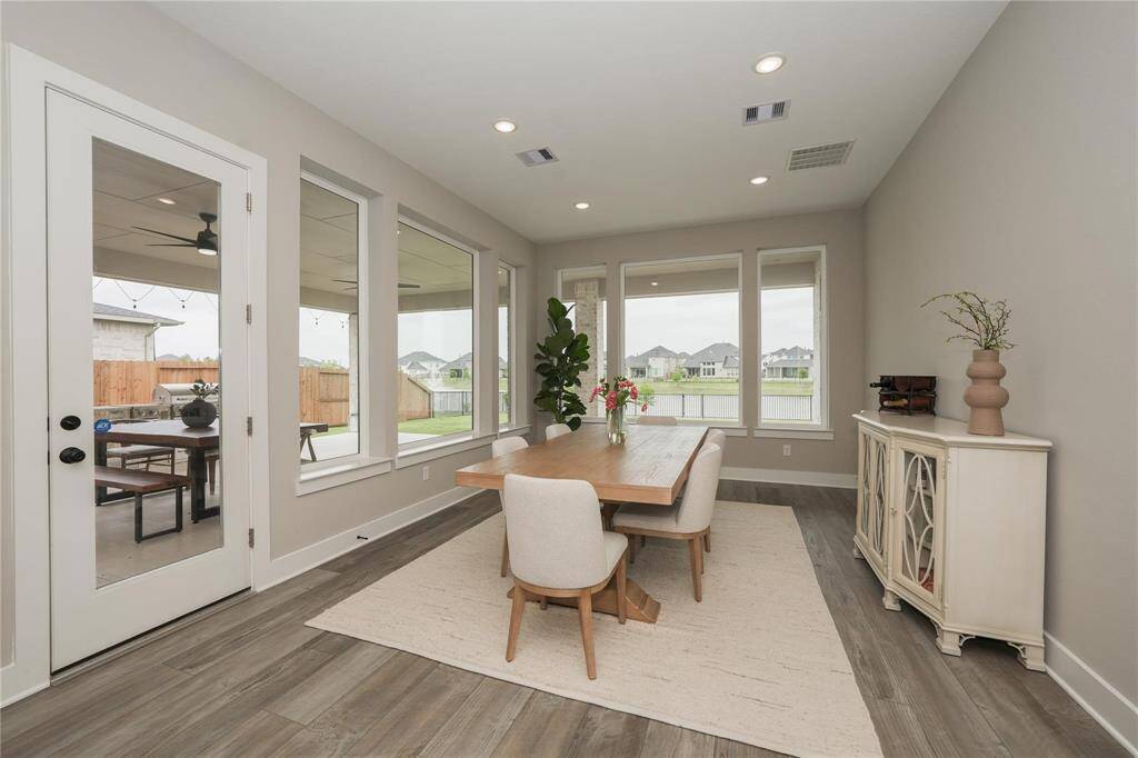 Bright dining area with large windows offering a scenic view, elegant wood flooring, and modern decor. The space features a wooden table, comfortable chairs, and a chic side cabinet, creating a cozy and inviting atmosphere.
