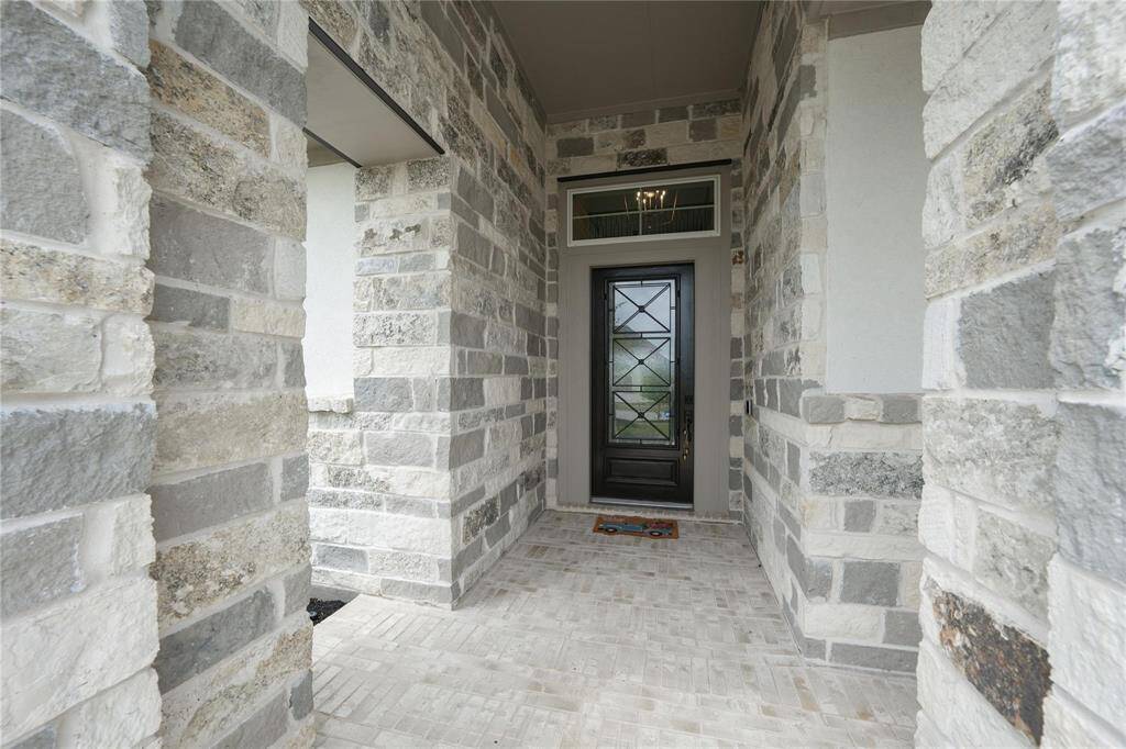 This photo showcases a welcoming entrance with a stone façade and a modern glass-panel door, offering a stylish and secure entryway to the home.