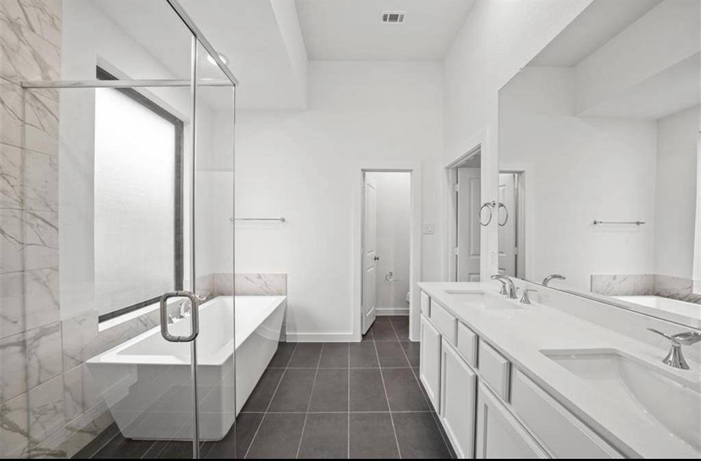 Black tile gives luxurious feeling to primary bathroom.