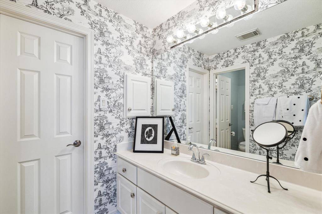 One side of the Hollywood bath with ample storage and counter space and pretty wallpaper.