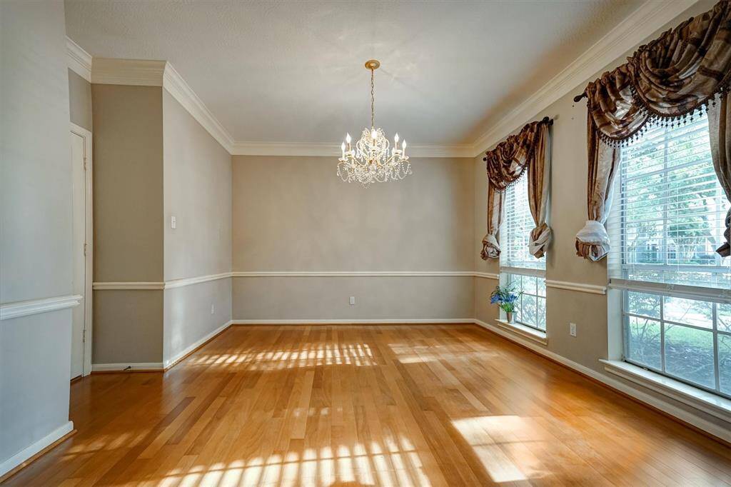 The formal dining room exudes charm and sophistication, featuring large double windows that fill the space with natural light. Framed by elegant window curtains, the windows offer a graceful view while enhancing the room’s warm ambiance.