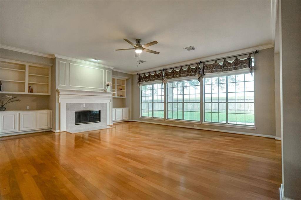 The spacious and cozy family room, featuring a charming fireplace as the focal point. Rich wooden flooring adds warmth and character