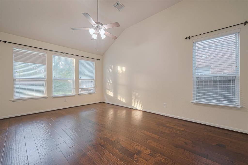 What a wonderful place to come home to, this stunning primary suite greets you with gorgeous wood floors, a warm custom paint, high ceiling, ceiling fan with lighting, large windows with blinds allowing in natural light brightening up this spacious primary bedroom, with extra space for a seating area.