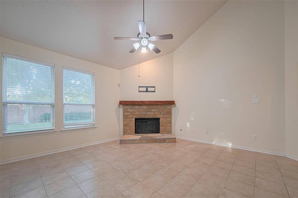 This family room is more like a GREAT room featuring a stunning fireplace with mantel detailing, custom paint, soaring high ceiling, dark stained ceiling fan, and an amazing wall of windows providing a lovely view of your backyard to keep an eye out on the kids or pets playing