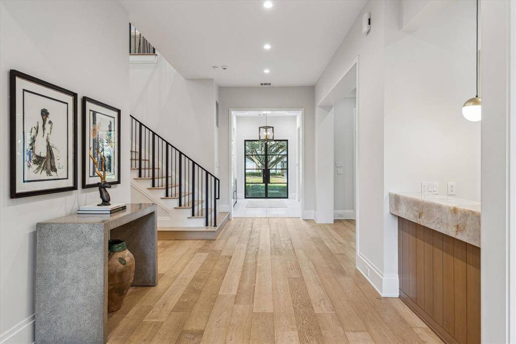 The spacious foyer is enhanced by a sophisticated wet bar to the right and a grand staircase to the left. This inviting entryway establishes a seamless connection to the home's primary gathering spaces, enhancing both function and style for effortless entertaining.