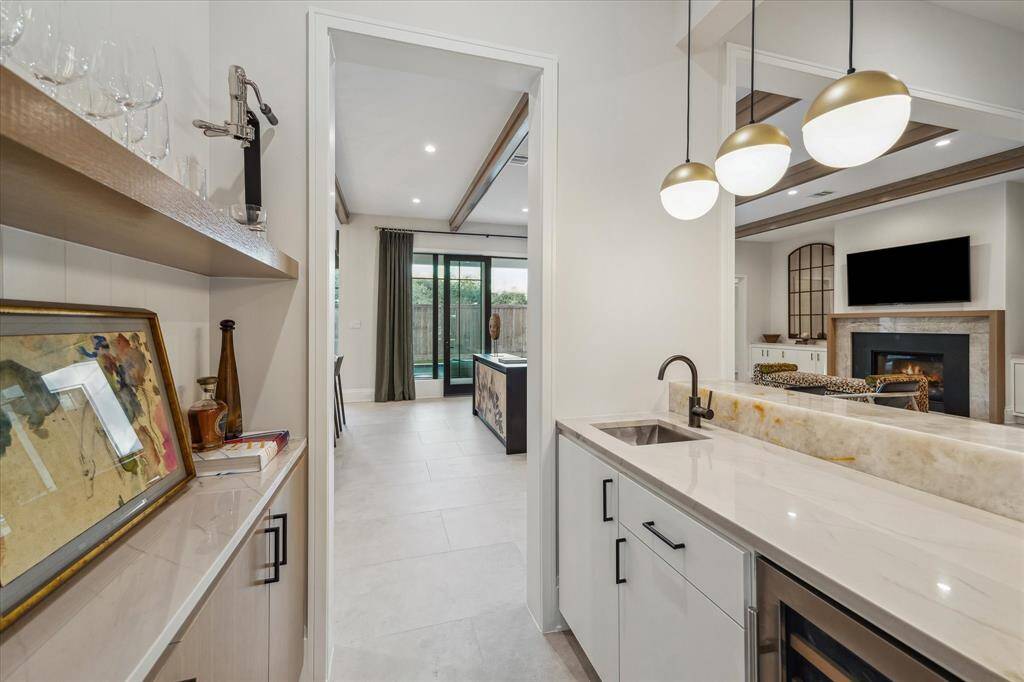 The wet bar connects the family room to the dining areas, blending style with functionality. With quartzite countertops, onyx bar detailing, and designer pendant lighting, this elevated space is perfect for entertaining.