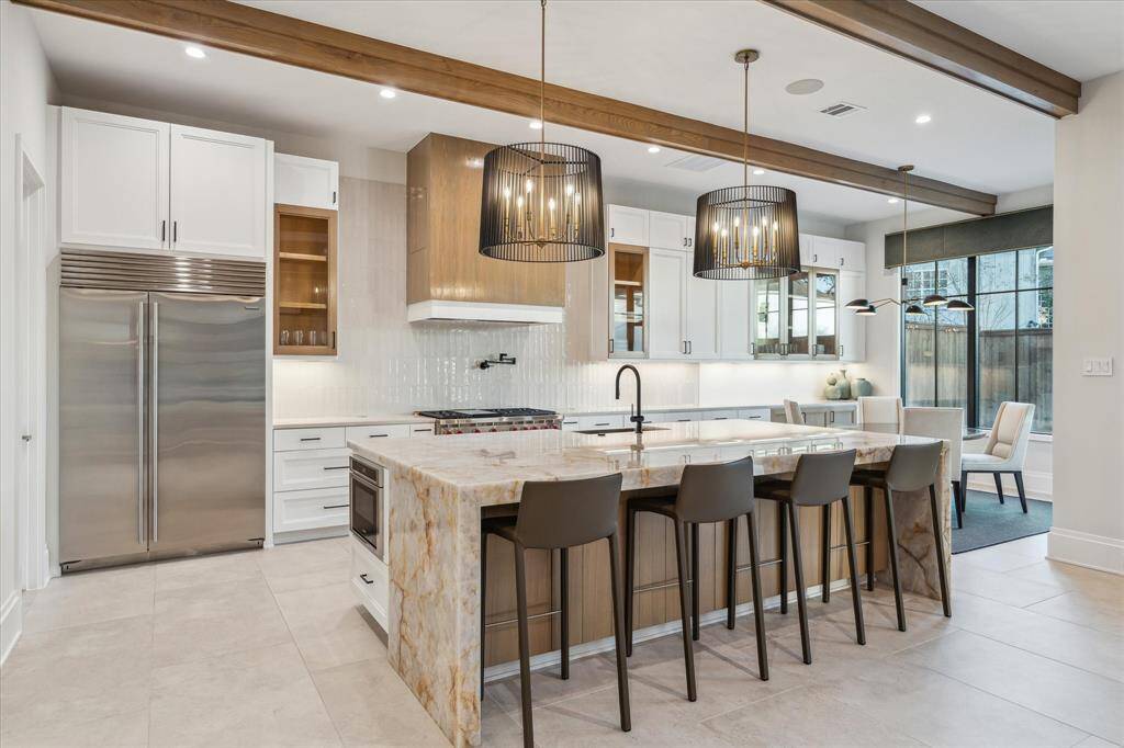 The well-appointed kitchen and breakfast room offer seamless connectivity, abundant storage, and tranquil pool views. Designer lighting and thoughtful finishes enhance the room’s bright and airy ambiance.