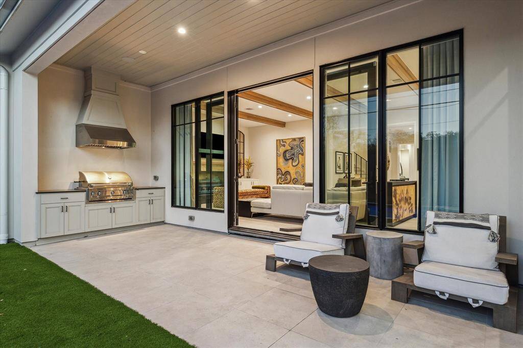 The covered patio offers a spacious outdoor living area with a summer kitchen, ceiling fan, and ample seating. This space is ideal for entertaining year-round.