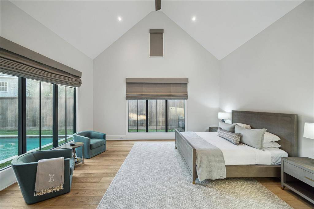The luxurious primary suite boasts soaring vaulted ceilings, custom window treatments, and serene pool views. This tranquil retreat offers a restful ambiance enhanced by thoughtful design details.