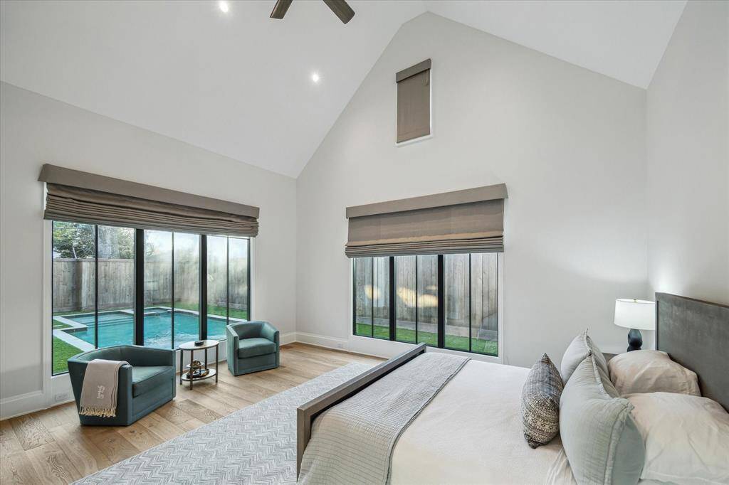 The primary bedroom’s expansive windows frame serene pool views, creating a tranquil retreat. Custom window treatments balance natural light with added privacy.