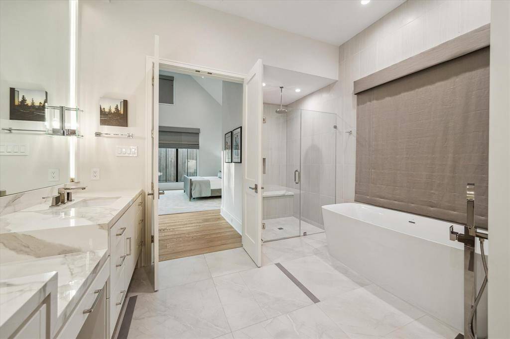 The expansive primary bathroom features a designer soaking tub, seamless walk-in shower, and ample storage. Polished nickel finishes add refinement to this spa-inspired retreat.