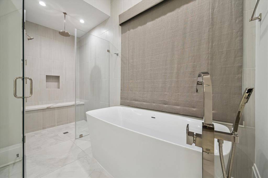 The primary bathroom’s luxurious design includes a freestanding soaking tub, marble mosaic shower flooring, and polished nickel fixtures. This thoughtfully designed space evokes a peaceful, spa-like experience.