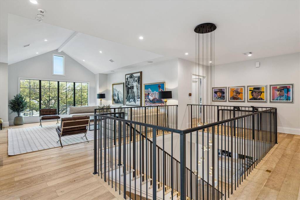 he upstairs hall leads to a spacious game room, featuring vaulted ceilings, engineered white oak flooring, and ample space for recreation or relaxation. Its open layout offers flexibility for various activities.