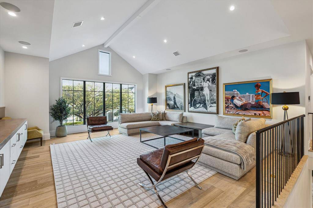 The expansive upstairs game room offers a built-in floating media console, custom wood detailing, and vaulted ceilings. Its inviting design makes it a perfect space for gatherings and leisure.
