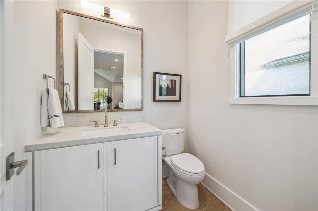 The upstairs powder room includes a sleek vanity with quartzite countertops, polished nickel fixtures, and custom sconces. Thoughtful design enhances this space’s elegant aesthetic.