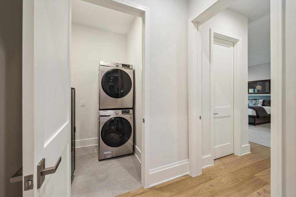 The upstairs utility room features Samsung stacked appliances, white oak flooring, and ample storage with custom cabinetry. Thoughtful design enhances efficiency.