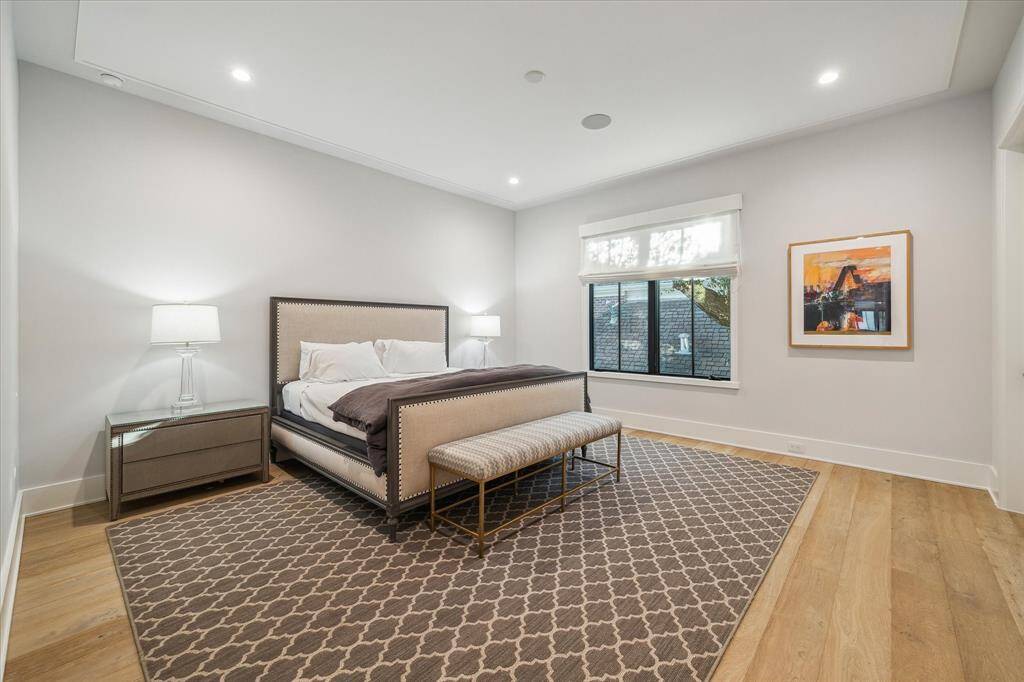 Guest bedroom #2 showcases custom ceiling detailing, warm wood flooring, and a spacious walk-in closet. Thoughtful finishes elevate the room's comfort and charm.