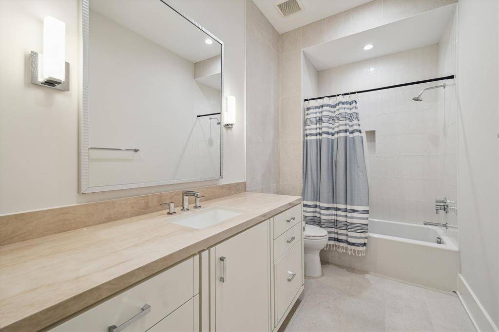 Guest bathroom #2 offers brushed nickel fixtures, quartzite countertops, and a porcelain tile tub/shower combo. Sleek finishes ensure both elegance and practicality.