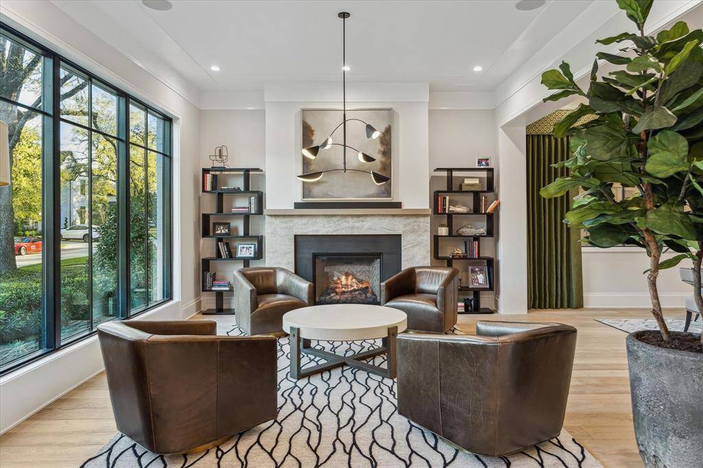 The formal living room exudes warmth with its quartzite fireplace surround, white oak mantel, and gas log fireplace. Expansive windows bathe the room in natural light, creating an inviting atmosphere for guests to gather and unwind.
