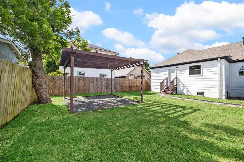Lounge by a fire pit or dine alfresco under this peaceful pergola and enjoy this spacious backyard with your furry friends.