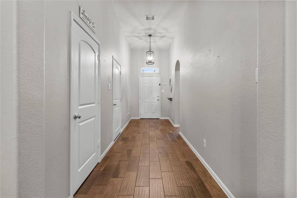 Spacious hallway entry leads past secondary bedrooms and the laundry room, opening into the heart of the home.