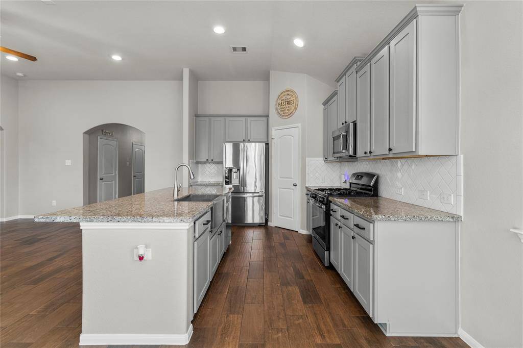 Spacious kitchen with room to cook, serve, and gather—featuring a farmhouse sink in the island and a view of the open living area.