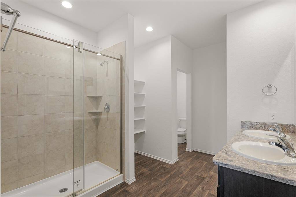 The primary bathroom features double sinks, upgraded quartz countertops, high ceilings, and a walk-in shower with tile surround recently renovated to include a glass door!