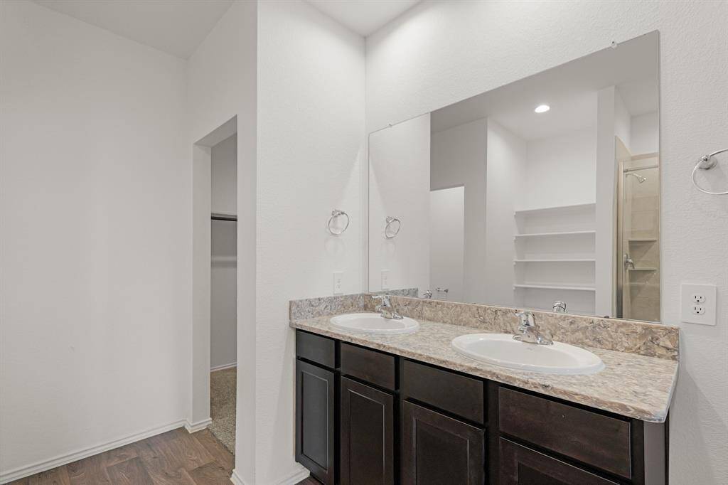 You'll love getting ready in this light and bright primary bathroom! The primary bathroom includes a large vanity with dual sinks, granite counters, large mirror, and wood cabinets.