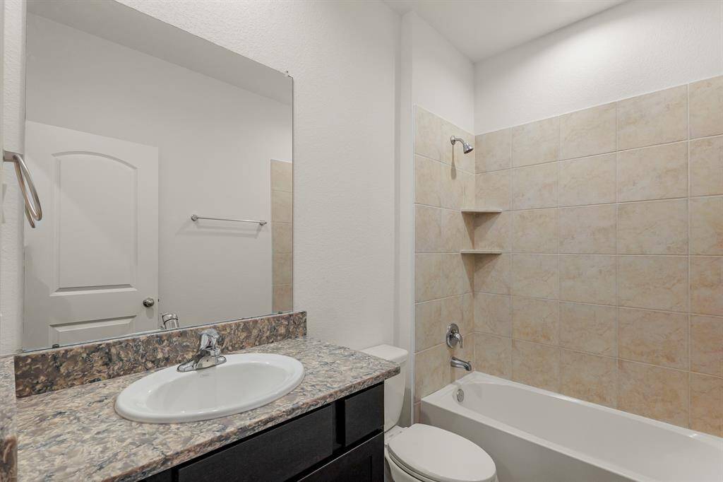 Downstairs secondary bathroom features dark cabinets, upgraded quartz countertops, and a shower and tub combo with tile surround!