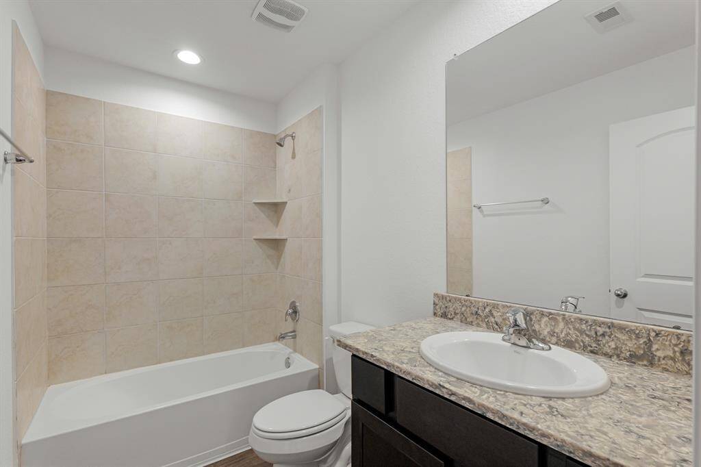 This full bathroom is located off the hall of the secondary bedrooms making it easy to share and get ready. It features a large vanity, white cabinets, quartz countertops, and a large combination tub and shower.
