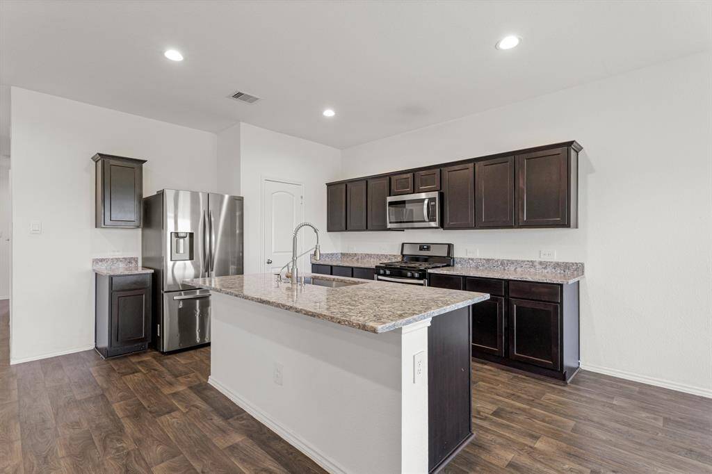 This spacious kitchen features high ceilings, dark cabinets, granite countertops, SS appliances, recessed lighting, and large kitchen island with sink bowl, pull out faucet, and breakfast bar!