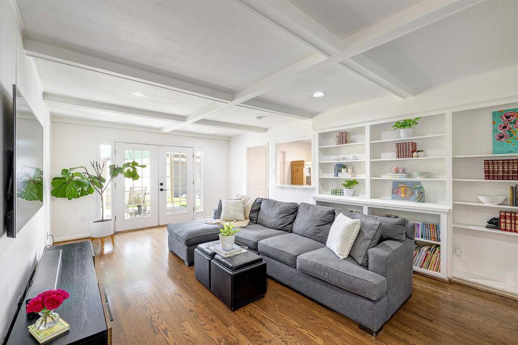 Cozy family room with built-in bookshelves, coffered ceiling and French doors overlooking the backyard