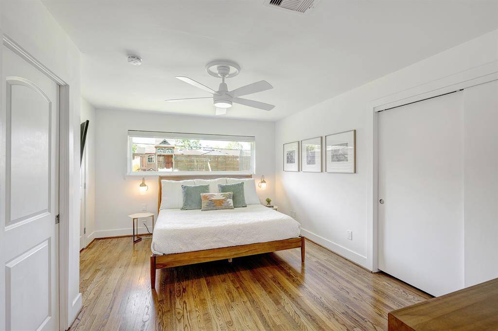 Beautiful primary bedroom with hardwood floors, soundproof landscape window with custom black-out shade and two closets with built-in organizers.