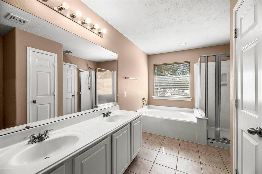 The primary bath features dual vanities, providing ample personal space along with an abundance of custom cabinetry for seamless organization.