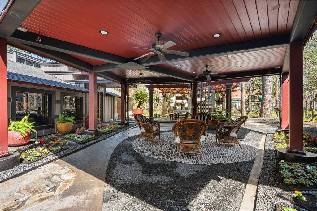 The backyard features a covered courtyard with beautiful landscaping, creating a serene outdoor retreat. A ceiling fan adds comfort, making it the perfect spot to relax and enjoy the surroundings in any season.