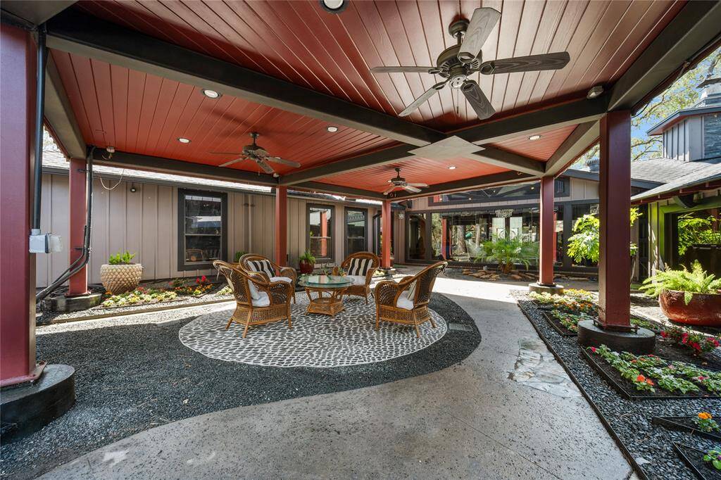 Another view of the courtyard showcases its lush landscaping and tranquil atmosphere, with carefully curated plants and stone pathways. The covered area offers a shaded retreat, perfect for outdoor dining or relaxation amidst nature.