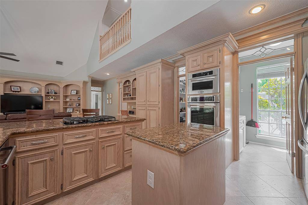 Double ovens, microwave and recently converted 4 burner gas range with downdraft.  Notice the decorative transom windows above the doorways to the utility room and pantry.