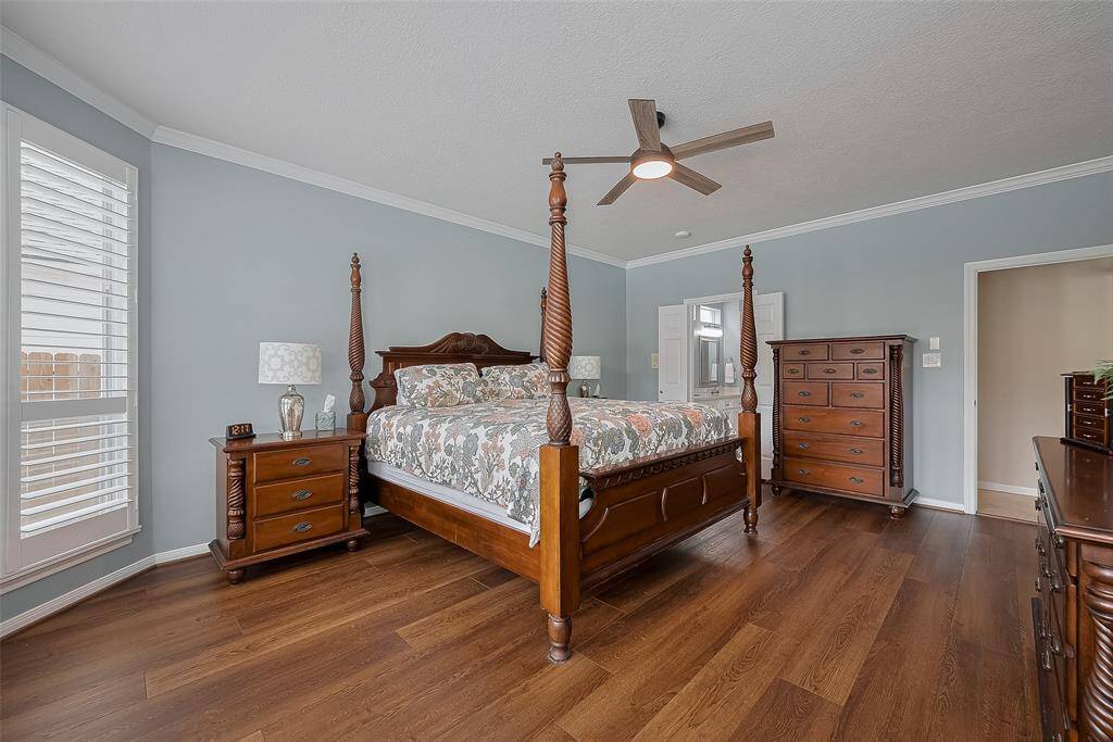 Primary bedroom down with large windows overlooking the beautiful backyard and pool.  Plantation shutters are featured on the windows here along with crown molding and updated ceiling fan.
