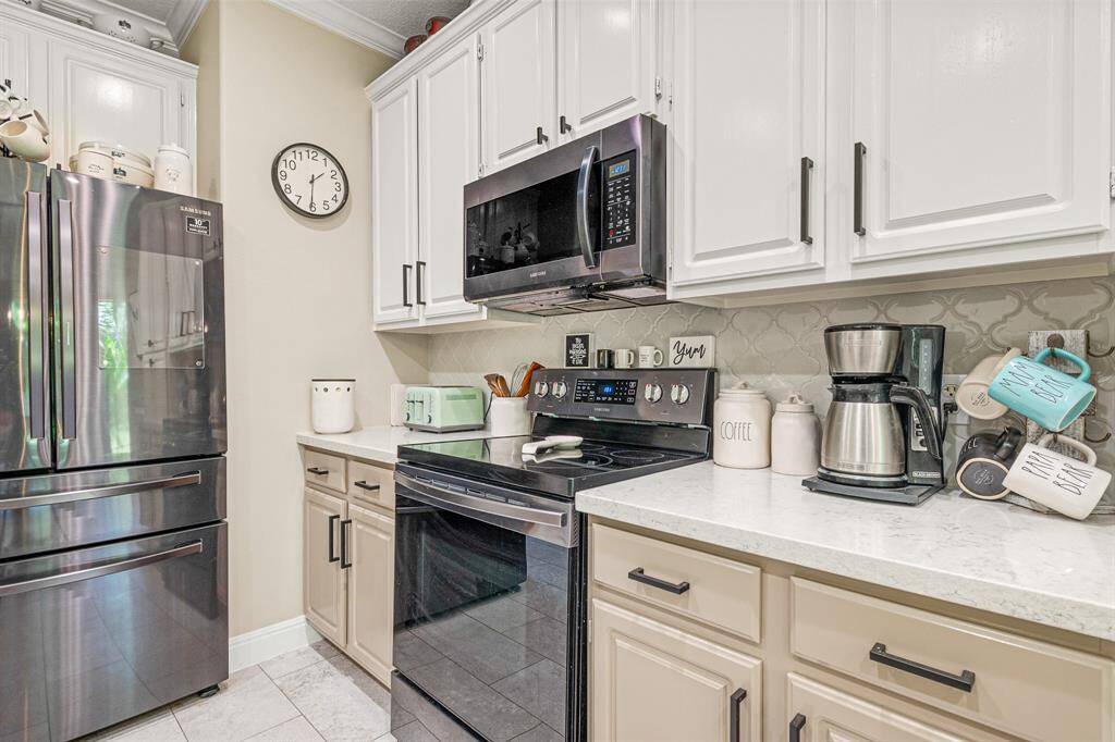 Featuring Beautifully Paired White and Beige Cabinets, Sleek Granite Countertops and the Eye Catching Detail of Decorative Tile Backsplash.