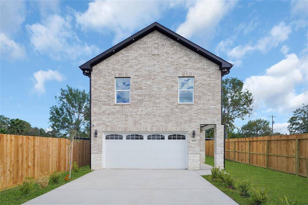 Charming two-story new construction with modern brick and siding facade, fenced yard, and lush green lawn.