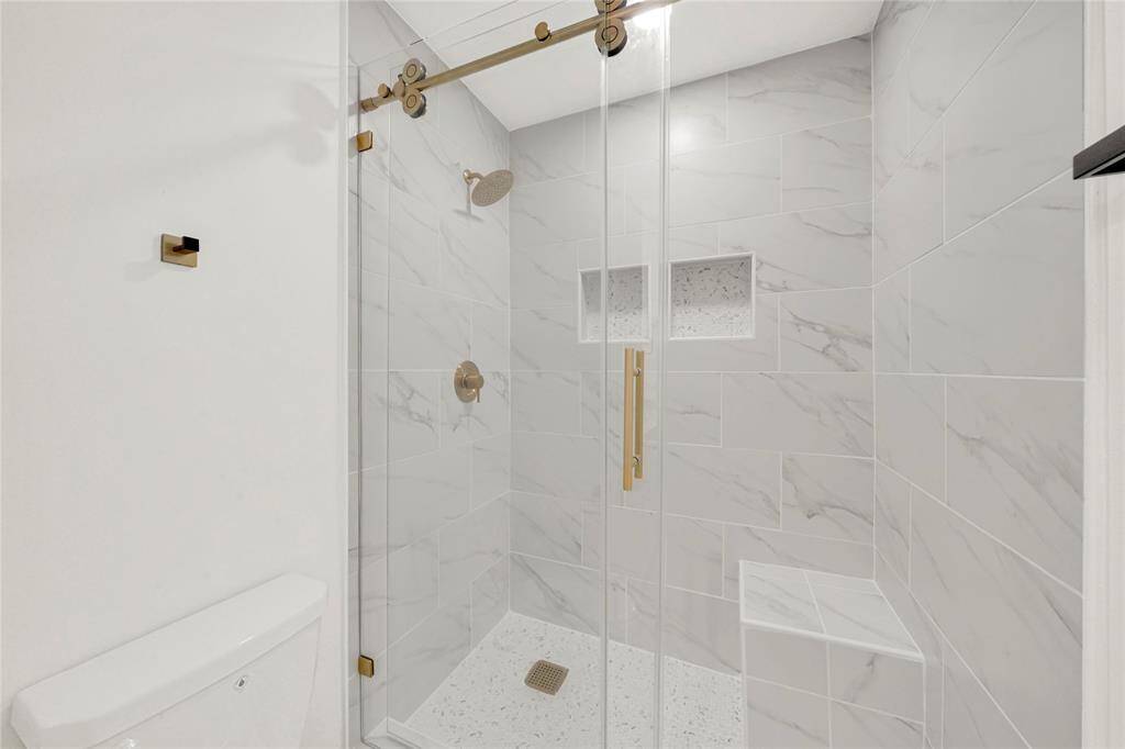 Walk-in shower with frameless glass door and sleek tile surround.